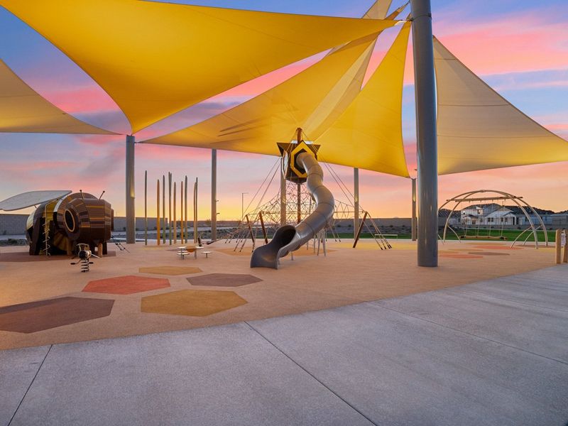 A statue of a bird under a colorful umbrella. A statue of a bird under a colorful umbrella.