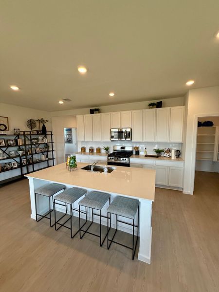A modern kitchen with sleek white cabinets, an island with seating, and open shelving. Bright and inviting space.