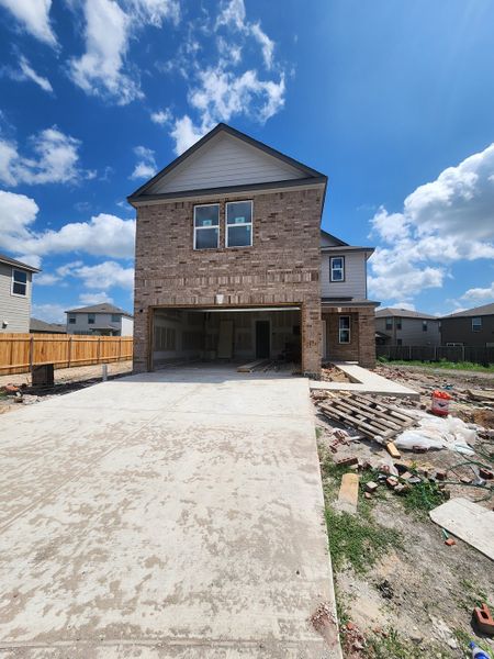A modern brick home with a spacious driveway in Presidential Meadows by KB Home (Manor, TX).