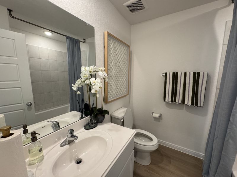 A chic bathroom with a sleek vanity, tiled shower, striped towels, and orchid decor for a refreshing ambiance.