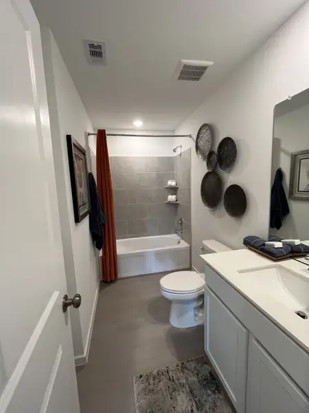A modern bathroom featuring a sleek vanity, gray tiles, vibrant red curtain, and artistic wall decor.