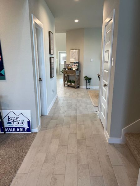 A welcoming hallway with wood-like flooring, neutral walls, and modern decor accents. A welcoming hallway with wood-like flooring, neutral walls, and modern decor accents.
