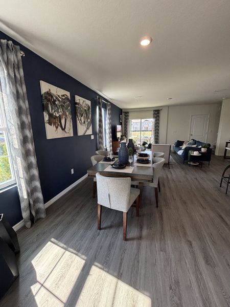 A spacious living room with navy accent walls, sleek flooring, and abundant natural light in Avian Pointe Townhomes by D.R. Horton (Apopka, FL).