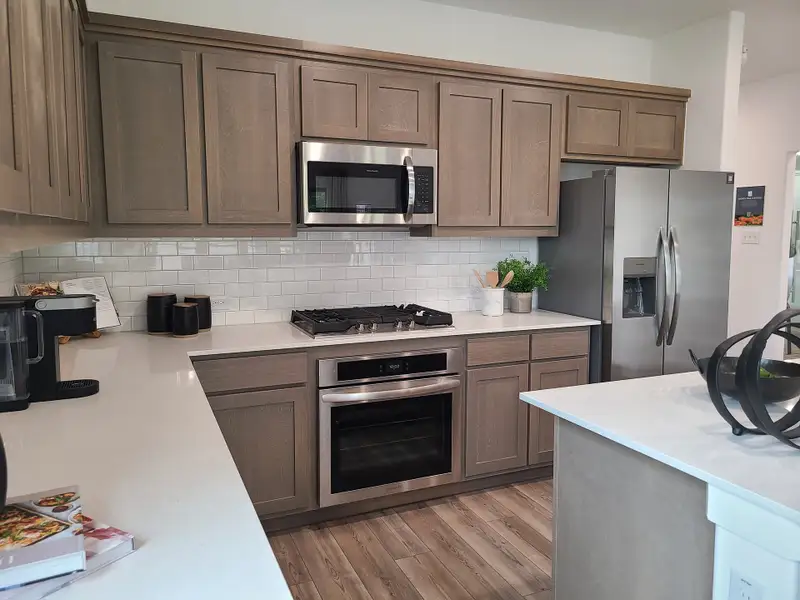 A modern kitchen featuring light wood cabinetry, stainless steel appliances, and sleek white countertops with a subway tile backsplash. A modern kitchen featuring light wood cabinetry, stainless steel appliances, and sleek white countertops with a subway tile backsplash.
