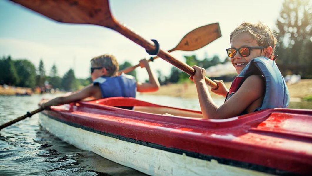 Two kids in a red and white canoe.