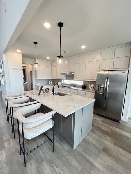 A modern kitchen with white cabinets, sleek countertops, bar seating, and stylish pendant lighting. A modern kitchen with white cabinets, sleek countertops, bar seating, and stylish pendant lighting.