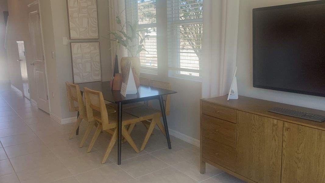 A cozy dining area with a sleek black table, wooden chairs, and a modern sideboard, featuring natural light and tasteful decor.
