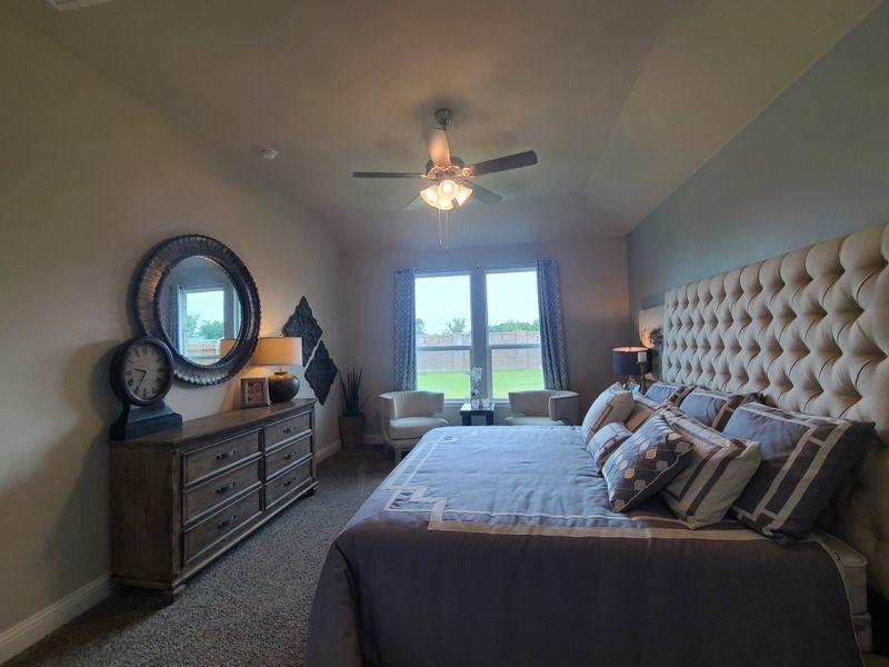 A cozy bedroom with a tufted headboard, elegant dresser, and ample natural light from large windows. A cozy bedroom with a tufted headboard, elegant dresser, and ample natural light from large windows.