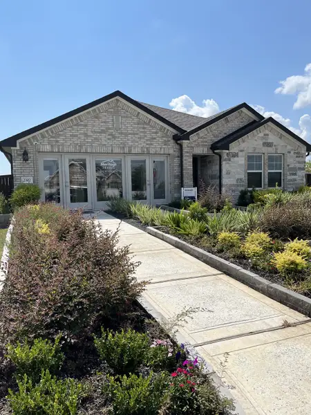 A beautiful brick home with manicured landscaping in the Southwinds community by Meritage Homes (Baytown, TX).