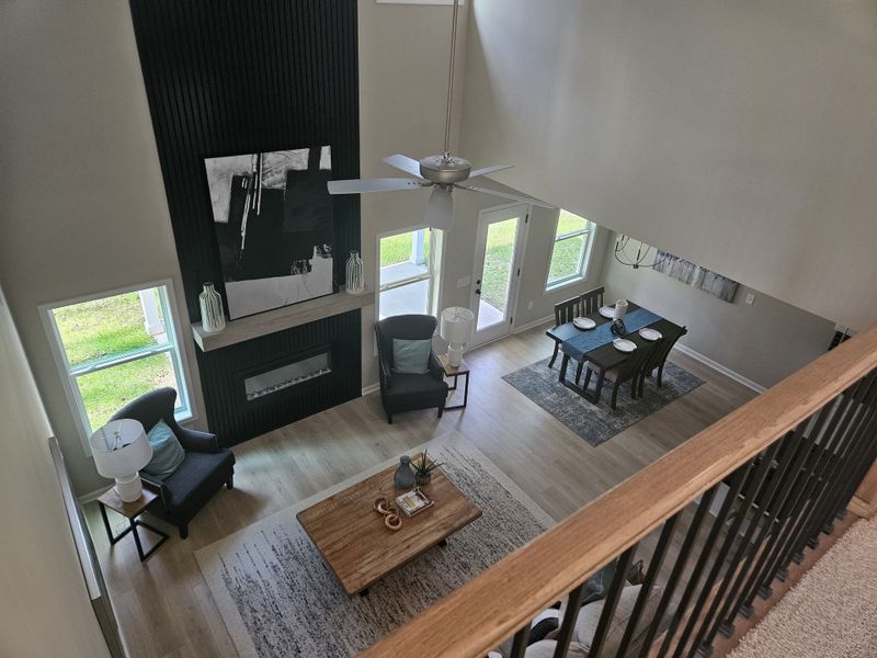 A top-down view of the living area with a black fireplace, cozy seating, and a dining area in the background.