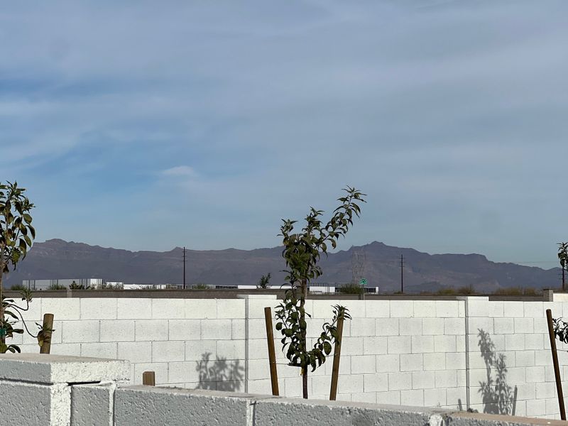 A scenic view of distant mountains beyond a white brick wall in The Estates at North Creek by New Home Co. (Queen Creek, AZ).