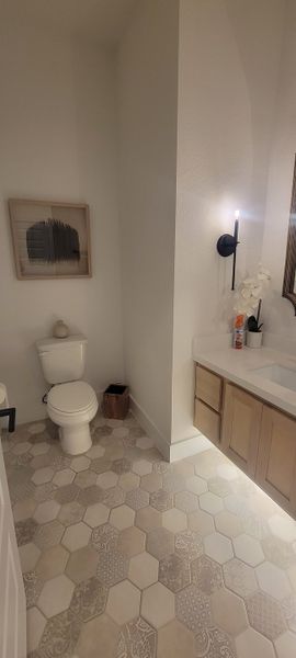 A modern bathroom featuring hexagonal patterned tiles, a sleek vanity with understated decor, and soft ambient lighting.