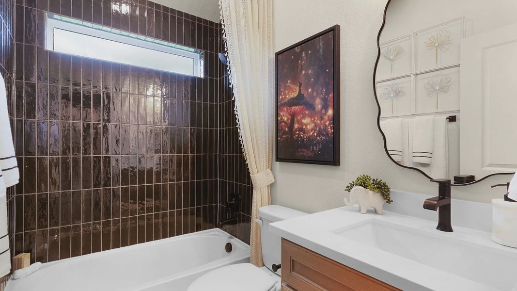 Secondary bath features a sleek tile finish, modern vanity, and a window at the shower/bath for natural light.
