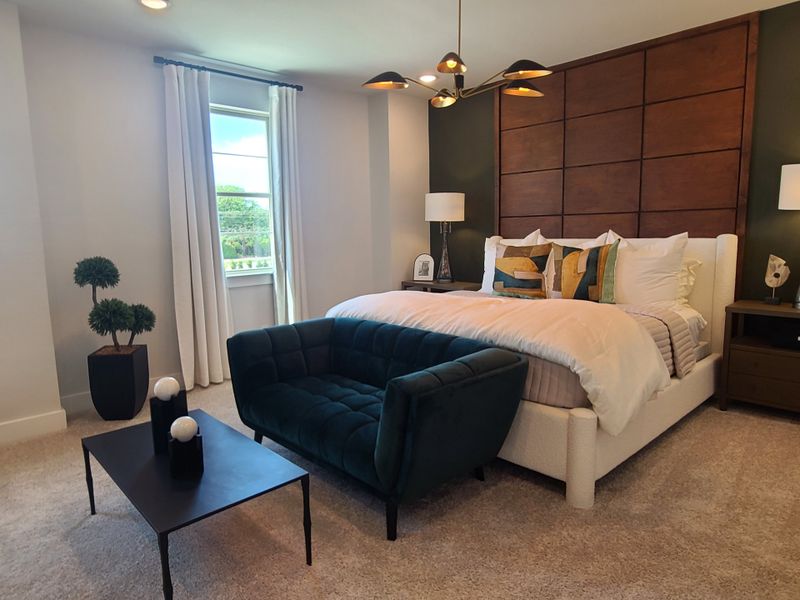 A cozy bedroom with a modern chandelier, upholstered bed, accent pillows, and a sleek coffee table.
