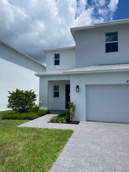 A modern white home with sleek lines and a tidy lawn in Symphony Place by Mizner Development (West Palm Beach, FL).