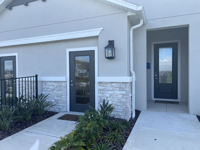 A modern home with a stone accent façade in St. John Preserve by Adams Homes, featuring sleek landscaping (Palm Bay, FL).