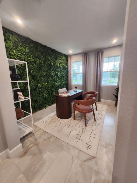 A modern office with a green accent wall, sleek desk, and stylish chairs, exuding a sophisticated, natural charm.