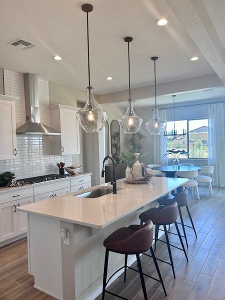 A modern kitchen with a sleek island, pendant lighting, white cabinetry, and stainless steel appliances.