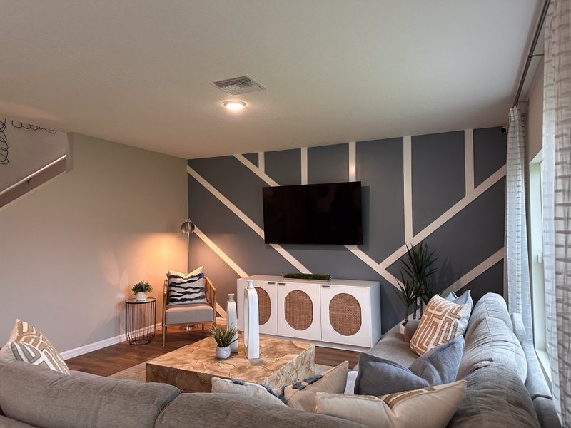 A cozy living room with a geometric accent wall, plush sectional, and stylish decor, perfect for relaxation and socializing.