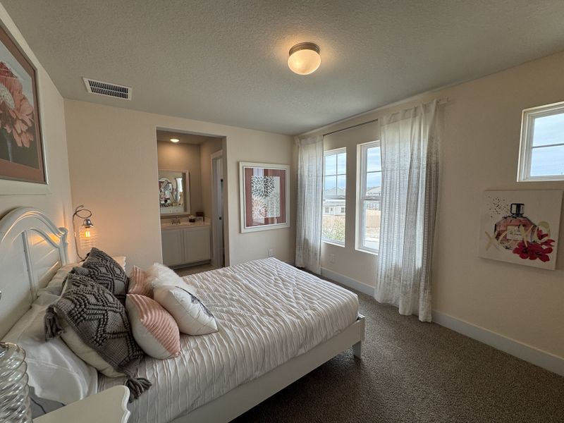 A cozy bedroom with plush bedding, soft lighting, and a vanity nook, complemented by large windows and elegant decor. A cozy bedroom with plush bedding, soft lighting, and a vanity nook, complemented by large windows and elegant decor.