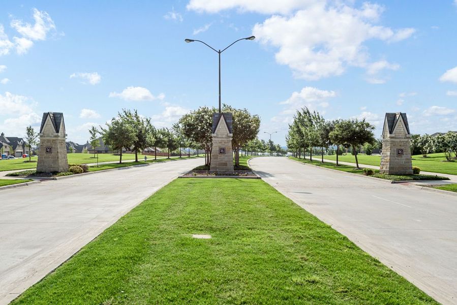 Subdivision entrance with three stone pillars, landscaped median, and tree-lined streets leading into the neighborhood. Subdivision entrance with three stone pillars, landscaped median, and tree-lined streets leading into the neighborhood.