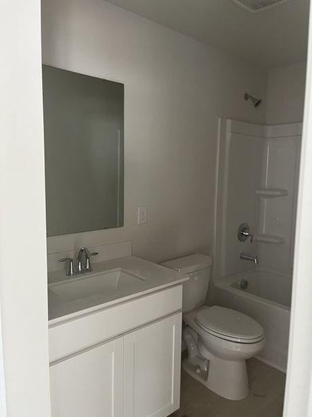 A sleek bathroom featuring a white vanity, integrated sink, large mirror, and shower-tub combo for modern convenience. A sleek bathroom featuring a white vanity, integrated sink, large mirror, and shower-tub combo for modern convenience.