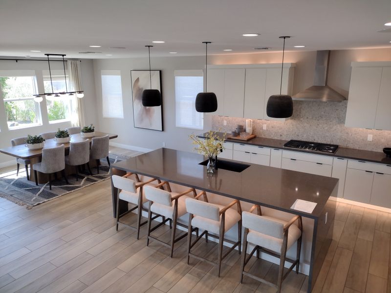 A modern kitchen with a large island, sleek cabinets, and a cozy dining area featuring stylish pendant lighting. A modern kitchen with a large island, sleek cabinets, and a cozy dining area featuring stylish pendant lighting.