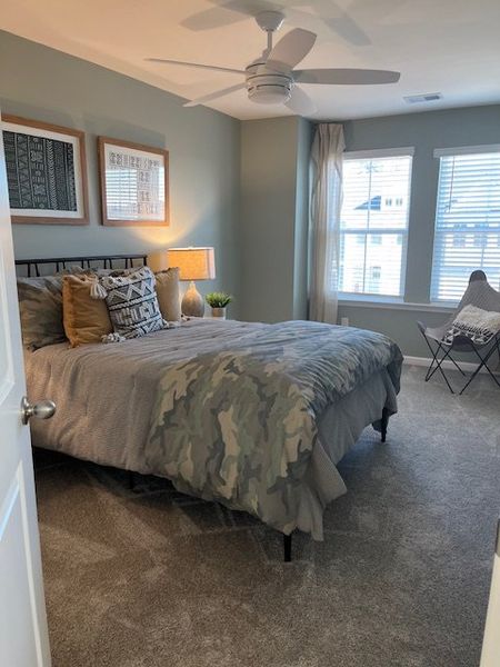 Cozy bedroom with soft carpeting, stylish accents, and ample natural light for a relaxing retreat.