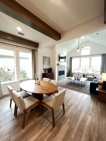 An inviting open-concept living space with a round wooden dining table, cozy seating, and large windows for natural light.