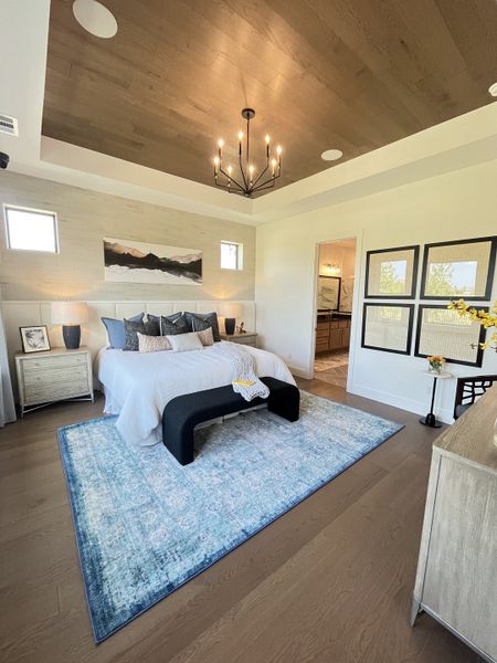 Elegant bedroom with a wood ceiling, modern chandelier, cozy rug, and stylish decor elements. Elegant bedroom with a wood ceiling, modern chandelier, cozy rug, and stylish decor elements.