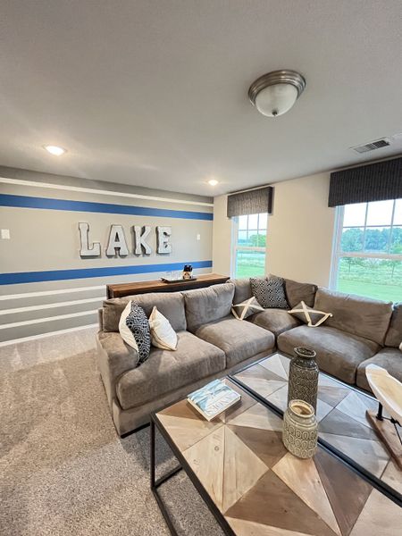 A cozy living room with a plush sectional sofa, patterned pillows, and a geometric coffee table in neutral tones.