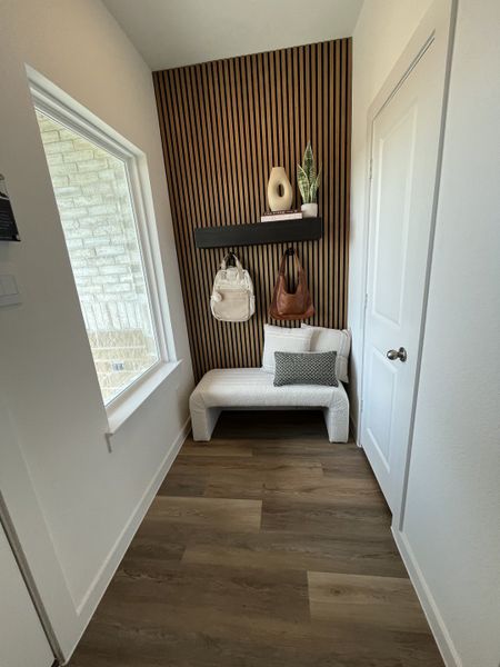 A stylish entryway featuring a slatted accent wall, sleek bench, and warm wood flooring, creating an inviting atmosphere.
