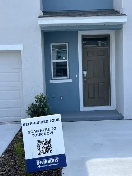 A modern entry at Chelsea Court by D.R. Horton in Tampa, FL, featuring blue accents and inviting landscaping.