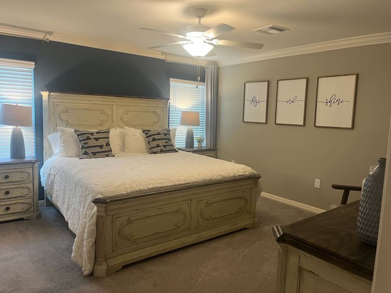 A cozy bedroom features a king-sized bed with a rustic headboard, dual nightstands, and elegant wall art.