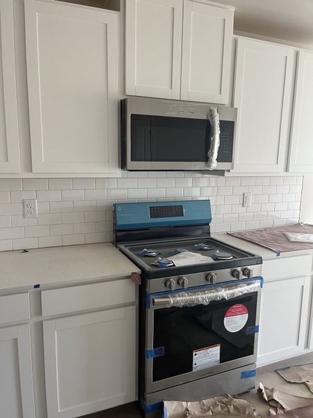 A modern kitchen with white cabinetry, a sleek stainless steel oven, and a subway tile backsplash. A modern kitchen with white cabinetry, a sleek stainless steel oven, and a subway tile backsplash.
