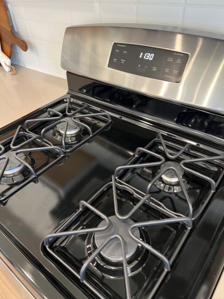 A modern kitchen features a sleek stainless steel gas stove with four burners and a digital display.