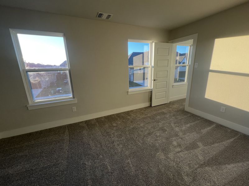 A bright room with carpeted flooring, two large windows, and a white paneled door inviting natural light.