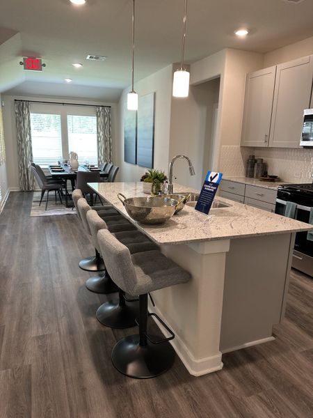 Modern kitchen with sleek island, cozy barstools, and pendant lighting, leading to a bright, elegant dining area. Modern kitchen with sleek island, cozy barstools, and pendant lighting, leading to a bright, elegant dining area.