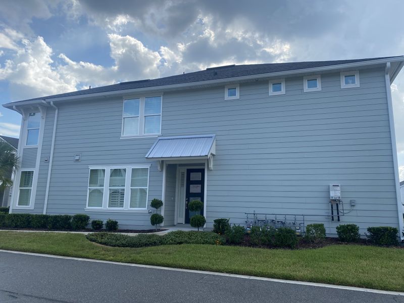 A modern light gray home with manicured shrubs and clean lines in West End at Town Center by ICI Homes (Ponte Vedra, FL).