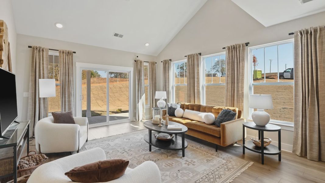 Large family room with backyard access, hardwood flooring, and multiple windows creating an airy feel in Moore, SC