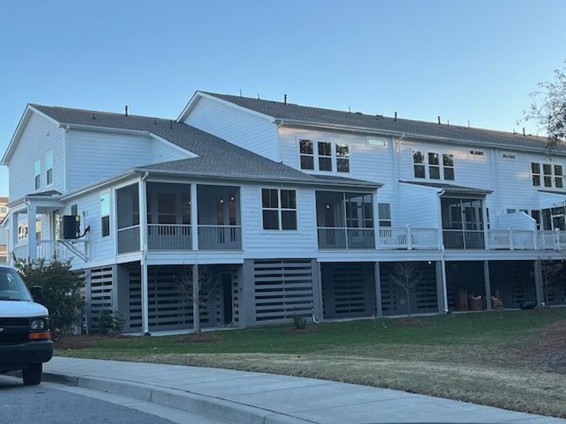 Charming white multi-story home with spacious porches in Liberty Hill Farm by K. Hovnanian® Homes (Mount Pleasant, SC).