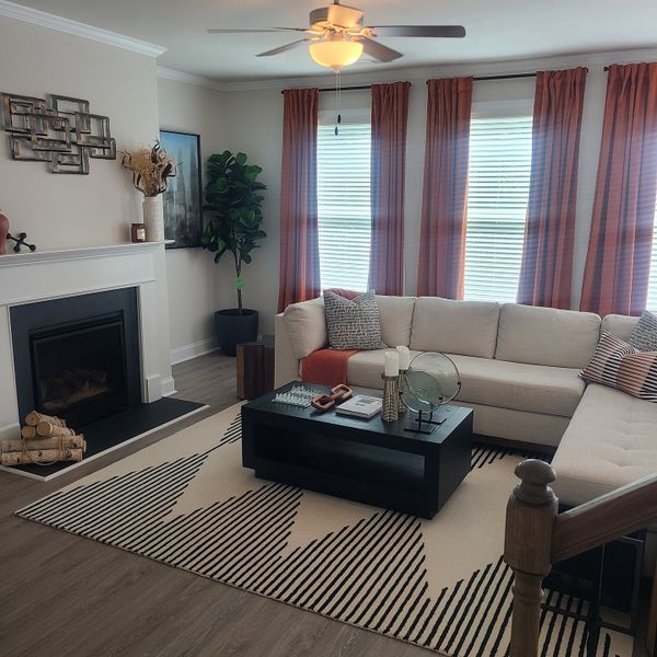 A cozy living room with a sectional sofa, fireplace, and modern decor accented by warm curtains and a stylish rug.