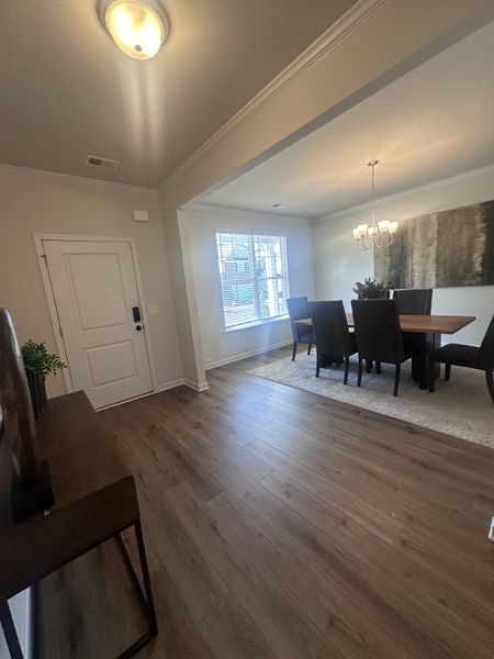 An elegant dining area with wood flooring, natural light, and modern chandelier, creating a warm and inviting atmosphere.