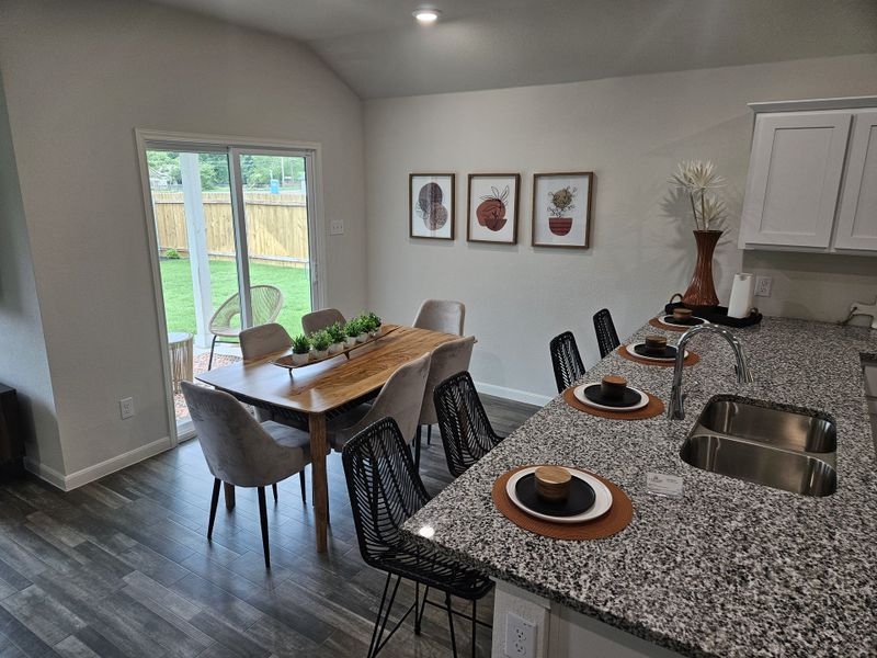 A modern dining area with sleek granite countertops, cozy chairs, and elegant decor accents.