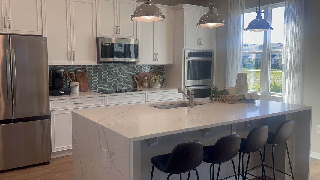 A sleek kitchen with a marble island, stainless steel appliances, and stylish pendant lighting.