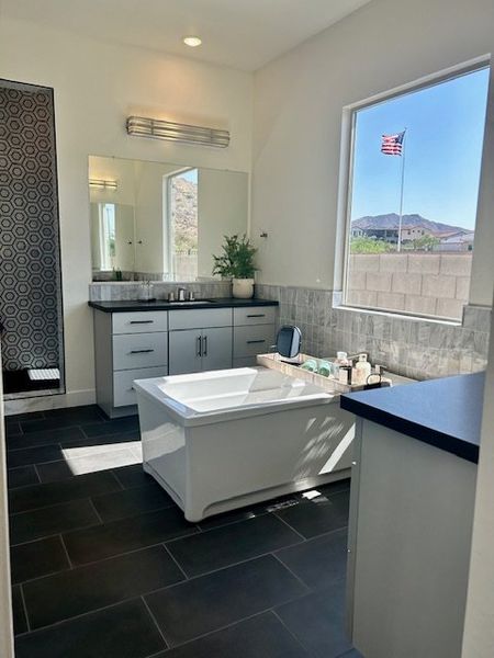 A modern bathroom featuring a sleek tub, double vanity, and large window with a scenic view.