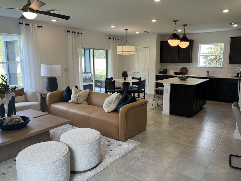 A modern open-plan living room with a tan leather sofa, cozy seating, and a sleek kitchen with dark cabinetry. A modern open-plan living room with a tan leather sofa, cozy seating, and a sleek kitchen with dark cabinetry.