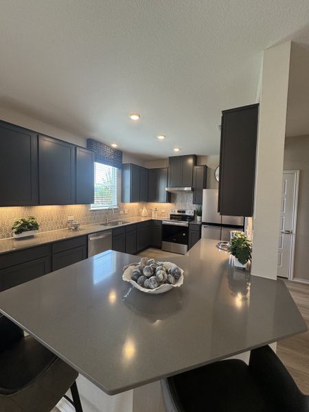 A modern kitchen featuring dark cabinets, sleek countertops, and ambient lighting with stylish accents. A modern kitchen featuring dark cabinets, sleek countertops, and ambient lighting with stylish accents.