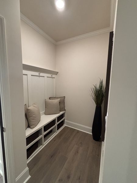 A cozy mudroom with elegant wood flooring, built-in bench seating, and decorative cushions.