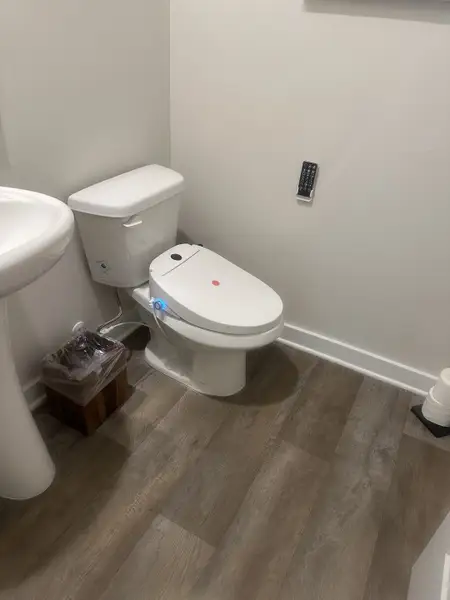 A modern bathroom with sleek fixtures, a smart toilet, and wood-style flooring. A modern bathroom with sleek fixtures, a smart toilet, and wood-style flooring.